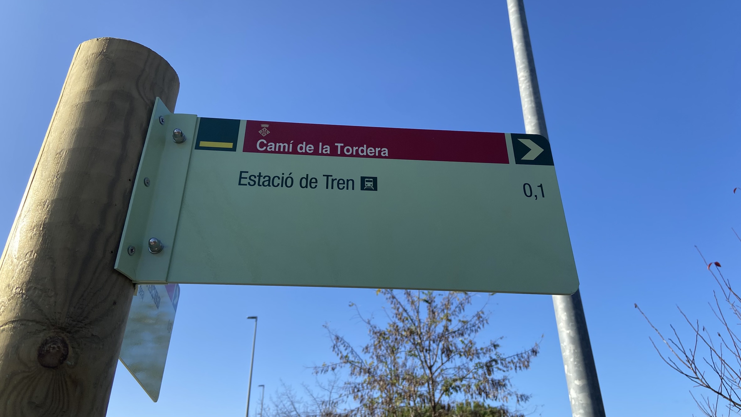 Foto: Tourdera. Senyalització entre l'estació de tren d'Hostalric i la Plaça dels Bous.